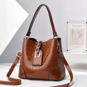 Detailed view of brown crocodile texture bucket bag with gold D-charm and shoulder strap