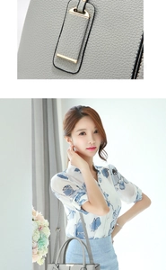 Close-up of grey lychee leather texture and golden metal buckle on women's tote bag