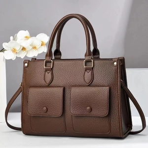 Détail du sac à main marron foncé grain litchi avec deux poches avant et boucles dorées