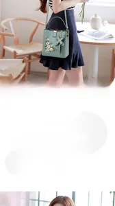 Détail d'un sac à main vert menthe avec broderie florale blanche et pendentif nœud 3D