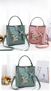 Détail de la broderie florale et du grand nœud sur les sacs seau verts et roses