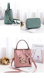 Détail de la broderie florale sur les sacs en similicuir rose et vert à rivets dorés