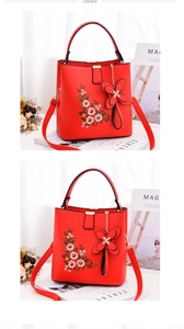 Détail macro du sac à main en cuir rouge avec broderie florale et pendentif décoratif