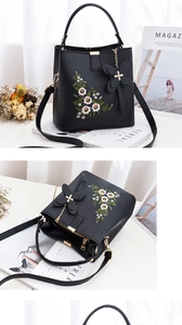 Détail de la broderie florale et du charme papillon sur sac à main en cuir noir
