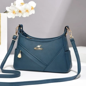 Detail of dark teal faux leather bag showing V-shaped stitching and gold hardware