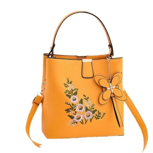 Sac à main brodé jaune avec motifs floraux et charm papillon sur fond blanc