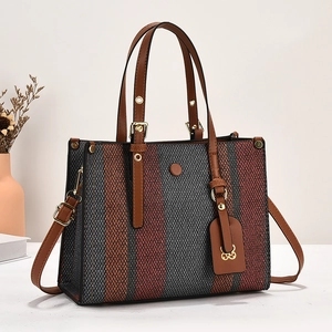 Close-up of tricolor woven canvas tote bag with brown leather straps and metal hardware