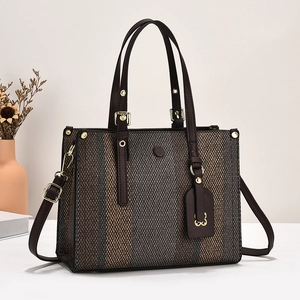 Detail of color-block canvas tote bag with brown leather handles and gold hardware