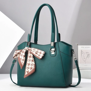 Detail of dark green pebble leather handbag featuring a stylish houndstooth bow and handles
