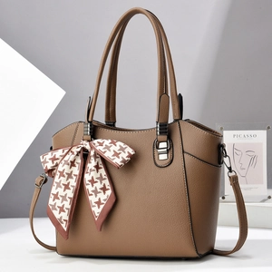 Close-up of litchi texture brown leather tote bag with silk houndstooth bow detail