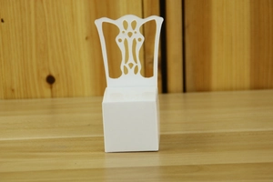 Detailed laser-cut hollow pattern on a white chair-shaped wedding favor box