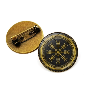Front and back detail of a bronze Viking compass brooch with a glass dome and safety pin