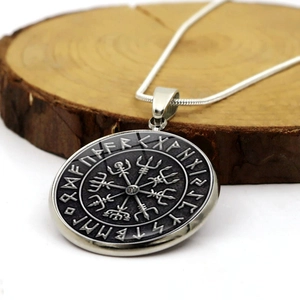 Detalle del colgante brújula vikinga Vegvisir con runas nórdicas sobre base de madera