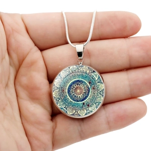 Close-up of circular mandala art pendant necklace with turquoise and gold patterns