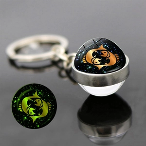 Macro view of Pisces constellation glass ball keychain showing green luminous effect
