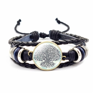 Detail eines mehrlagigen schwarzen Lederarmbands mit Lebensbaum unter Glaskuppel