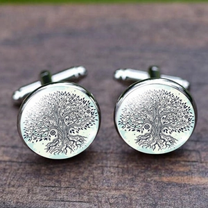 Silver tree of life cufflinks with green glass cabochon on rustic wood background