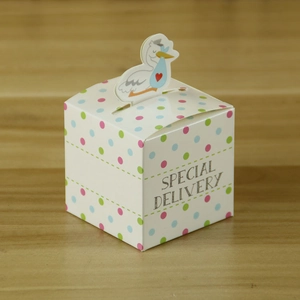 Detailed view of white polka dot gift box with stork topper for baby shower favors