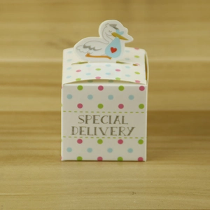 Polka dot baby shower favor box with stork topper on a wooden background