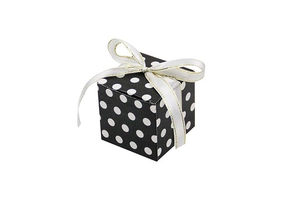 Macro view of square gift box with black white polka dots and gold-edged ribbon bow