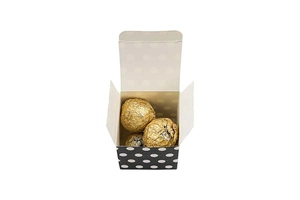 Macro view of square candy box with white dots holding three gold foil chocolates