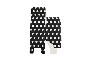 Flat lay of unfolded black and white polka dot paper candy box showing fold lines