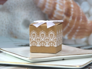 Close-up of square kraft candy box with white lace pattern and decorative silk bow