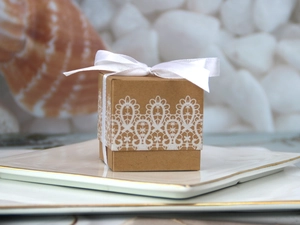 Close-up of square kraft paper candy box with white lace print and satin ribbon bow