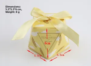 Macro detail of octagonal yellow wedding favor box with golden ribbon and feather pattern