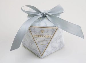 Detail of octagonal marble pattern gift box with silver ribbon bow and sweet gift tag
