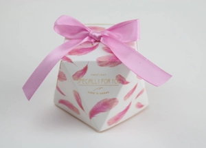 Close-up of octagonal gift box with pink feather print and satin ribbon bow detail