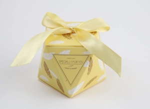 Close-up of yellow octagonal gift box with feather patterns and light yellow satin bow