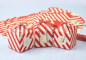 Detail van rood-wit gestreepte adventskalenderdoosjes met gouden cijferstickers 1 tot 3