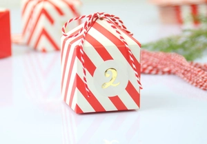 Detail van rood-wit gestreepte kerstdoos met goudkleurig nummer 2 en strik van touw