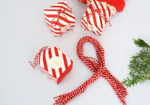 Detail van rood-wit gestreepte adventkalender snoepdoosjes met gouden cijfers en katoenen touw