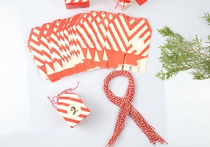 Platliggende weergave van rood-wit gestreepte DIY adventskalender geschenkdozen met katoen touw