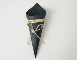 Close-up of black paper cone gift box with 'Especially for you' sticker and jute bow