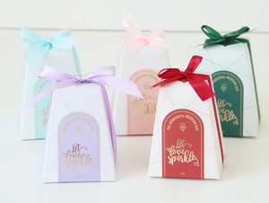 Details von trapezförmigen Gastgeschenkboxen mit Satinschleifen und Goldfolienprägung