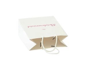 Close-up of a white bridesmaid gift bag with pink The Bridesmaid lettering and rope handle
