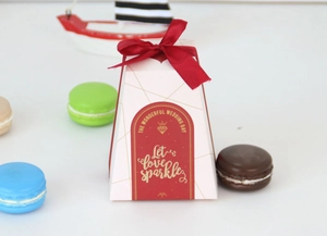 Detail der rosa pyramidenförmigen Hochzeit-Geschenkbox mit roter Schleife und Golddruck