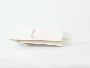 Detail view of a white bridesmaid paper gift bag with elegant pink lettering