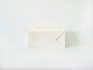 Detail of white paper bridesmaid gift bag with pink lettering and sturdy rope handles