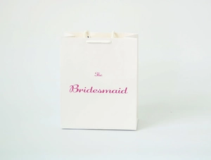 Detail of white paper gift bag with pink The Bridesmaid text and cord handles