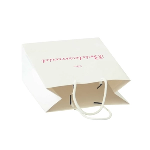 White paper bridesmaid gift bag with pink lettering and white rope handles