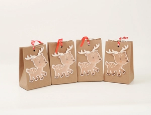 Detail of Christmas reindeer kraft gift bags with ribbed texture and red ribbon ties