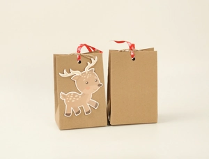 Detail of kraft Christmas gift bags with deer decor, ribbed texture, and festive ribbons
