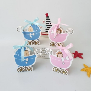 Detailed view of pink and blue stroller-shaped candy boxes with decorative ribbon bows