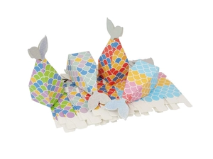 Detail of mermaid tail favor boxes with colorful fish scales and flat-packed DIY pieces