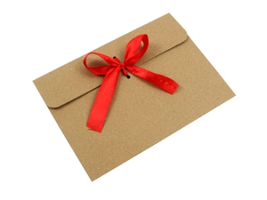 Close-up of kraft paper envelope with decorative red satin ribbon bow closure