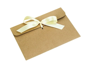 Close-up of brown kraft paper envelope with a cream white silk ribbon bow closure